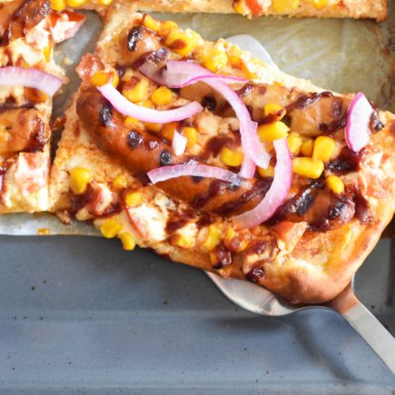 Op de barbecue gebakken pizza met chipolata en mais