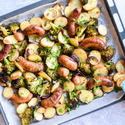 Traybake met worst, broccoli en rode ui